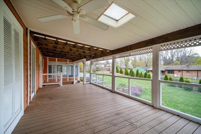 unfurnished sunroom with ceiling fan, a skylight, and a wealth of natural light
