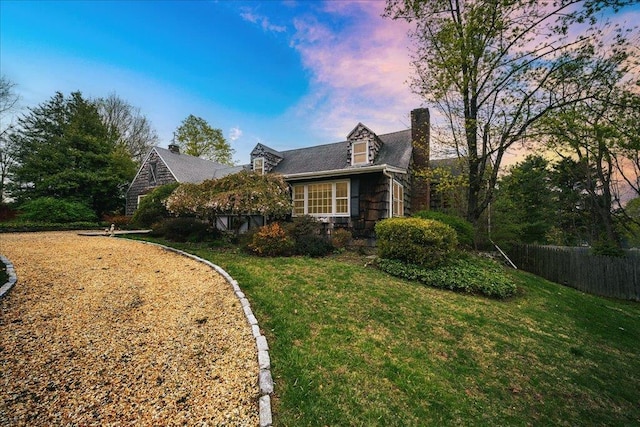 view of property exterior featuring a lawn, fence, and a chimney