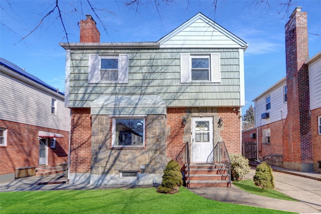 colonial house with a chimney, a front lawn, and brick siding