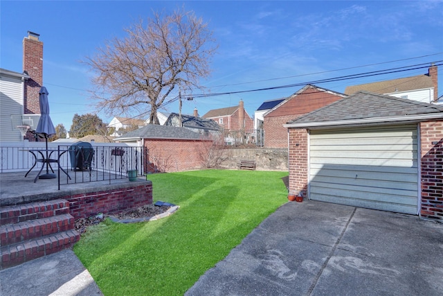 view of yard with a garage, a patio area, fence, and an outbuilding