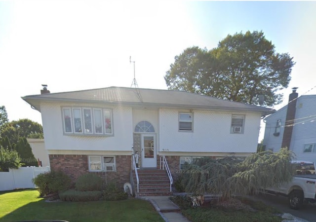 split foyer home featuring fence, a front lawn, and brick siding