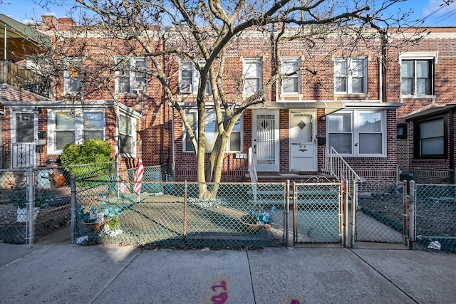 townhome / multi-family property featuring a fenced front yard, brick siding, and a gate