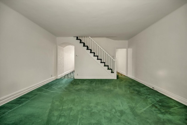 empty room with arched walkways, carpet flooring, stairway, and baseboards