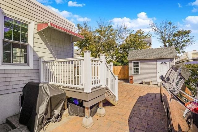 view of patio featuring a storage shed, an outdoor structure, fence, and a grill