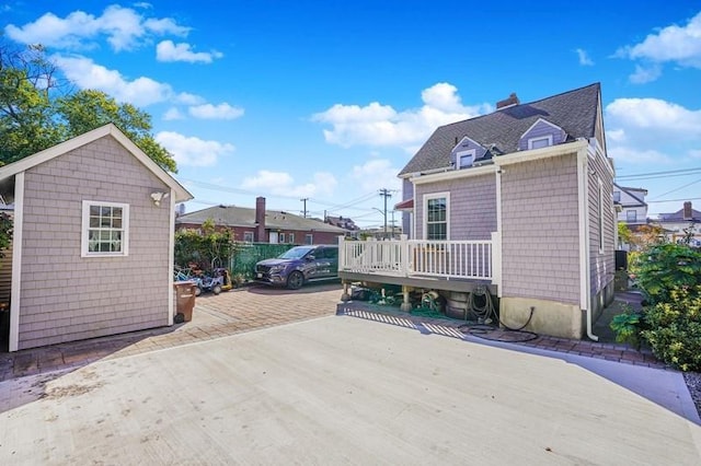 exterior space with a patio area, a chimney, a deck, and an outbuilding