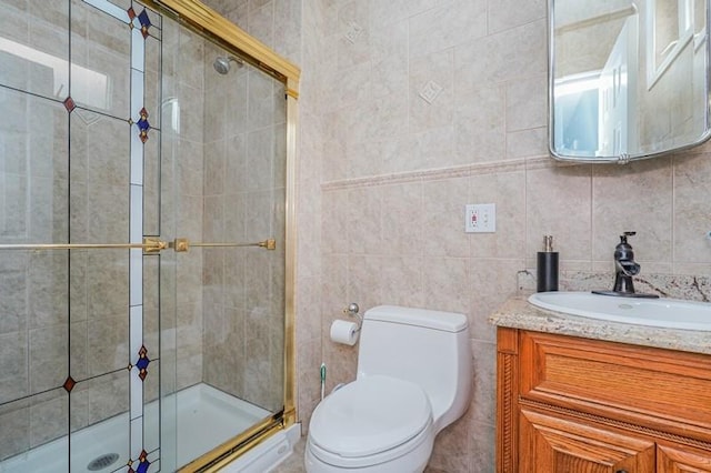 bathroom with toilet, a shower stall, tile walls, and vanity