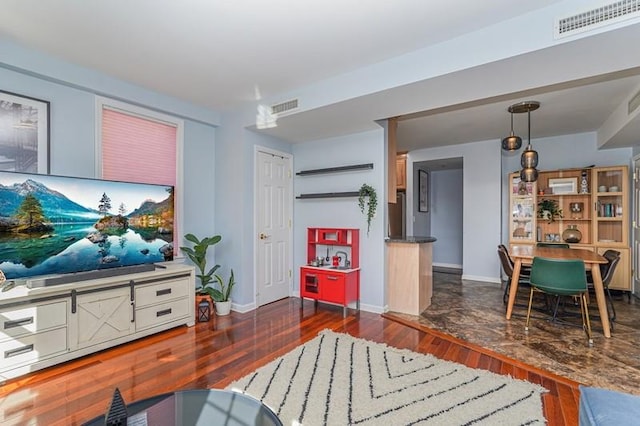 living room with wood finished floors, visible vents, and baseboards