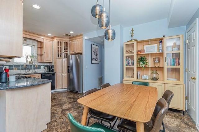 kitchen with black dishwasher, tasteful backsplash, glass insert cabinets, stone finish floor, and stainless steel fridge