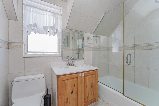 bathroom featuring tile walls, shower / bath combination with glass door, vanity, and toilet