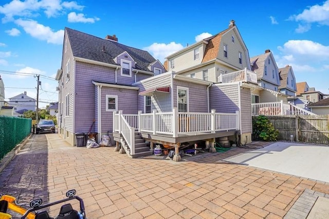 back of house with a residential view, a patio area, roof with shingles, and fence