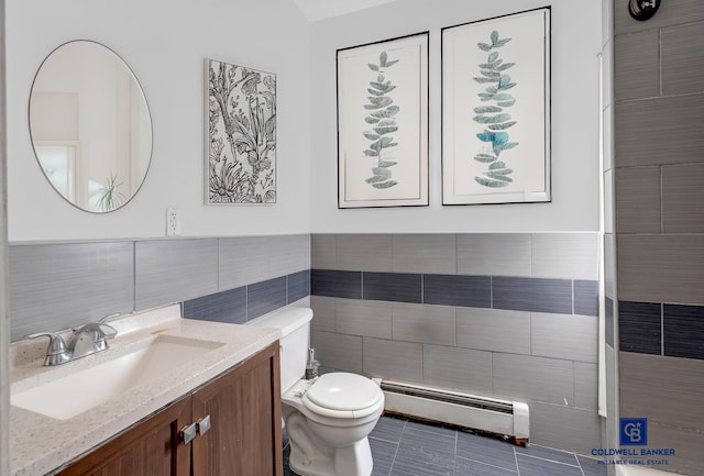 bathroom featuring toilet, a baseboard radiator, tile patterned flooring, vanity, and tile walls