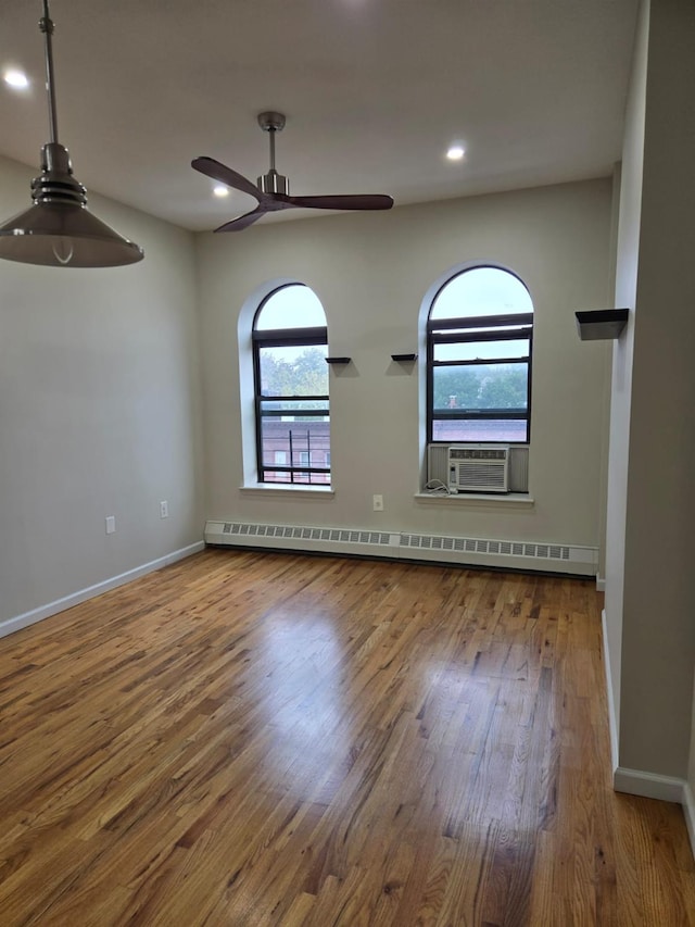 empty room featuring ceiling fan, baseboards, baseboard heating, and wood finished floors