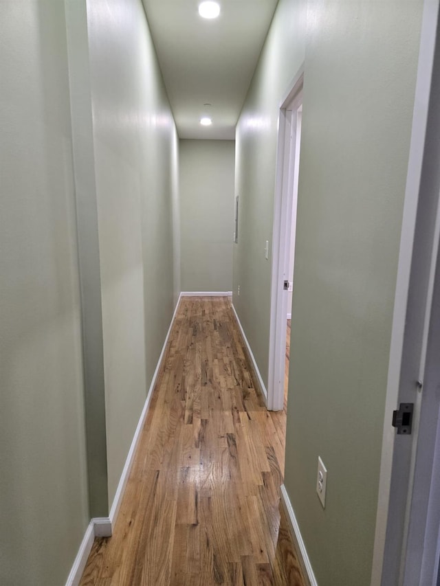 corridor with light wood-style flooring and baseboards