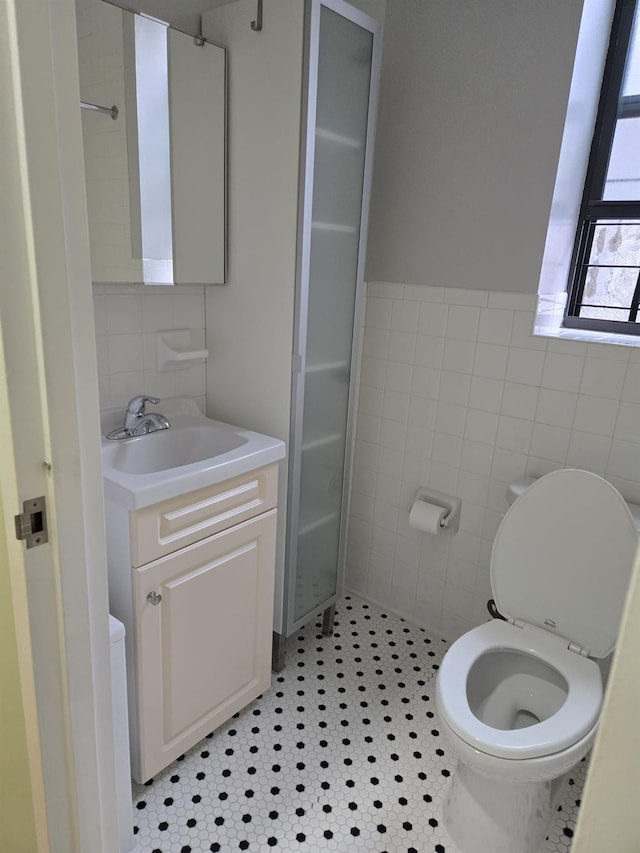 bathroom featuring toilet, wainscoting, vanity, and tile walls