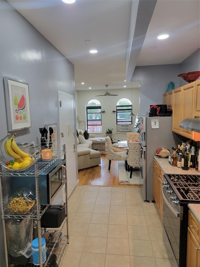 kitchen with range hood, freestanding refrigerator, light tile patterned flooring, light brown cabinets, and gas range