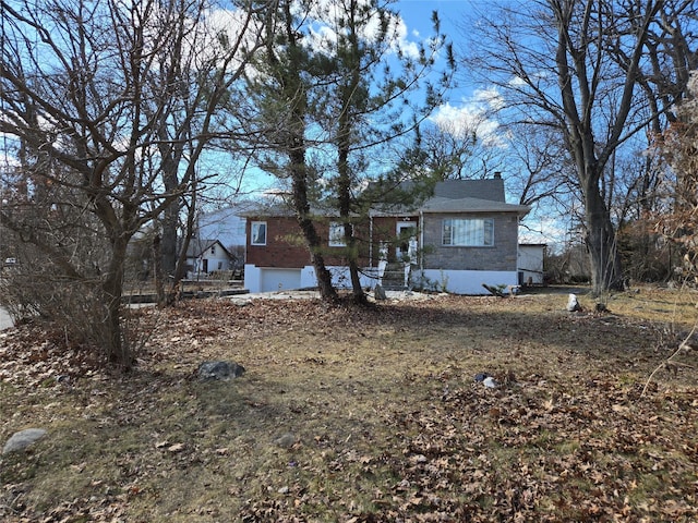 view of front of home featuring brick siding, a chimney, and an attached garage