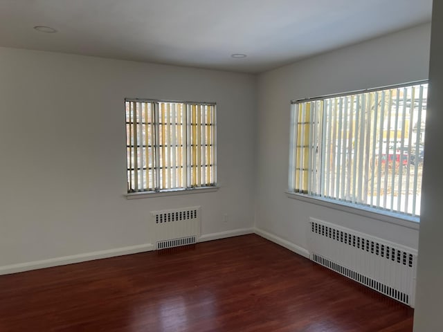 spare room featuring a healthy amount of sunlight, radiator heating unit, and wood finished floors