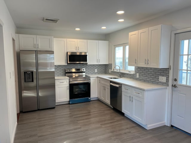 kitchen with stainless steel appliances, light countertops, visible vents, white cabinetry, and a sink