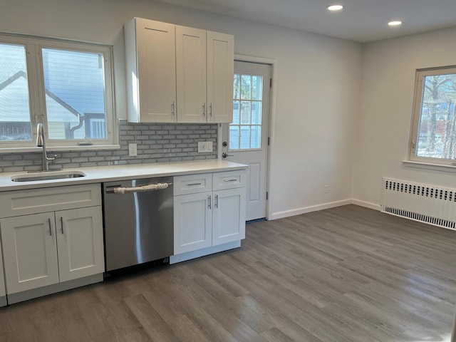 kitchen featuring light countertops, radiator heating unit, a sink, wood finished floors, and dishwasher