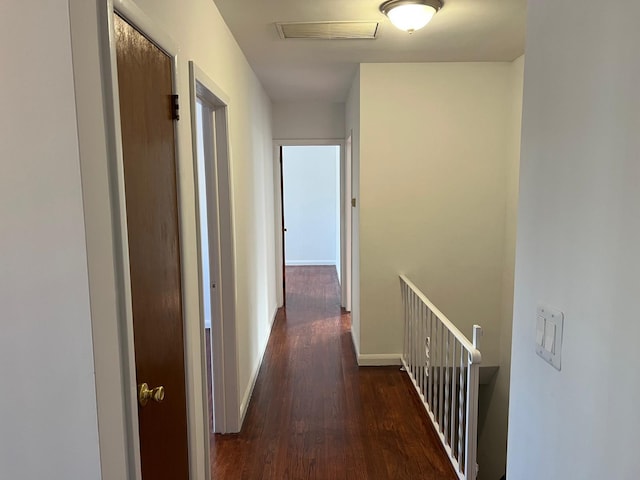 hallway with baseboards, visible vents, and wood finished floors