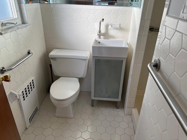 bathroom with a shower, tile walls, toilet, radiator heating unit, and vanity