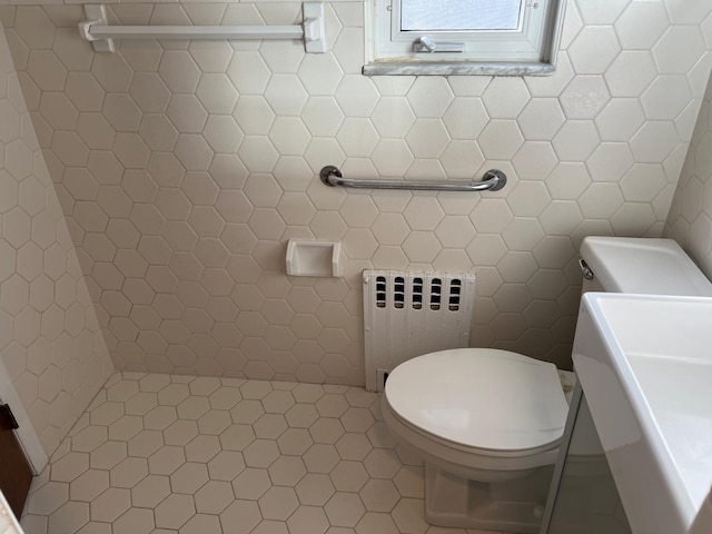 bathroom with radiator, toilet, and tile walls