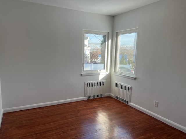 spare room with radiator heating unit, baseboards, and wood finished floors