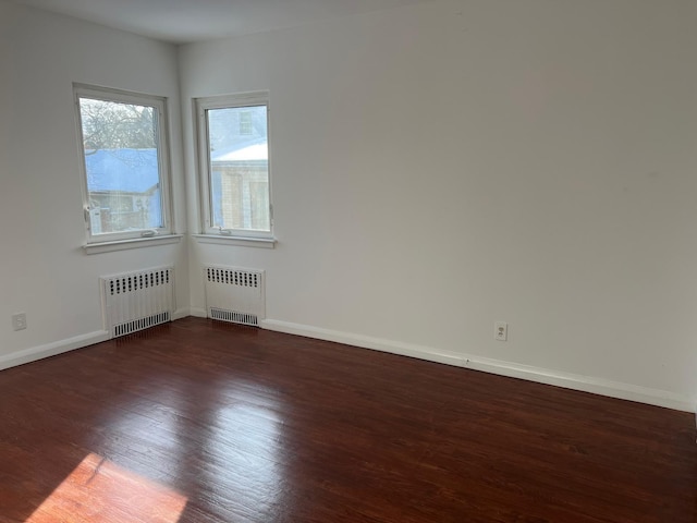 unfurnished room featuring radiator, baseboards, and wood finished floors