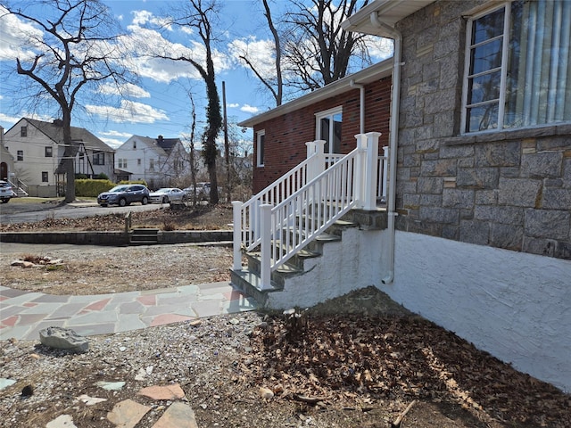 exterior space with a residential view, stone siding, and brick siding