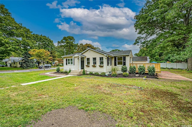 view of front of property featuring fence, a wooden deck, and a front lawn