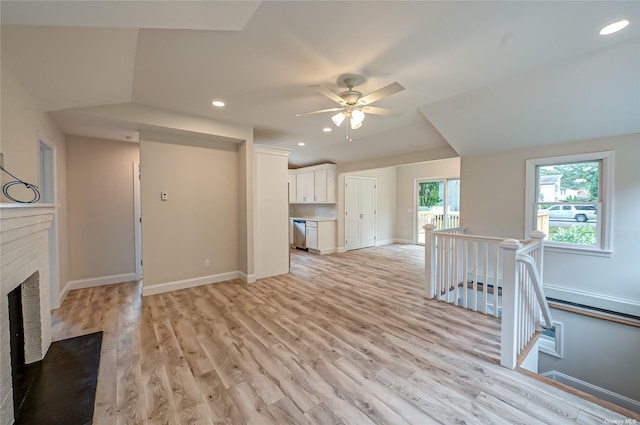 unfurnished living room with light wood-type flooring, a brick fireplace, baseboards, and recessed lighting