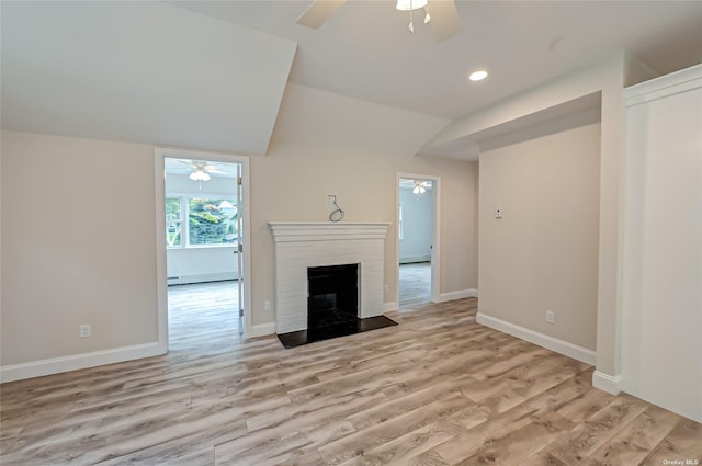 unfurnished living room with vaulted ceiling, light wood-type flooring, a ceiling fan, and a brick fireplace