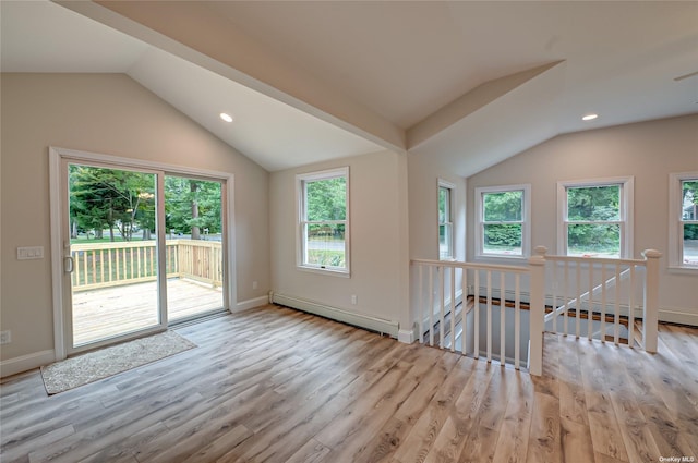 spare room with lofted ceiling, baseboard heating, light wood-type flooring, and baseboards