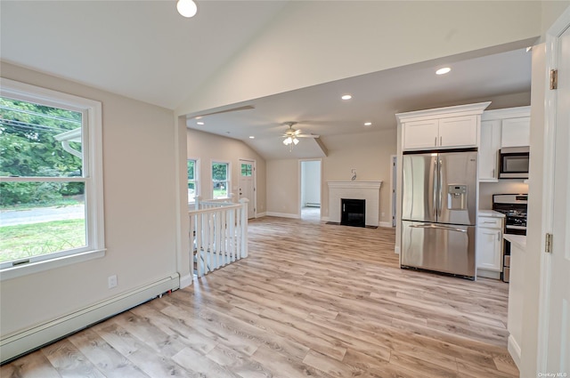 kitchen with light wood finished floors, appliances with stainless steel finishes, vaulted ceiling, baseboard heating, and white cabinetry