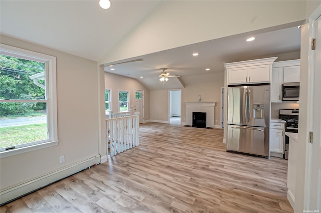 kitchen with a baseboard heating unit, white cabinets, vaulted ceiling, appliances with stainless steel finishes, and light wood-type flooring