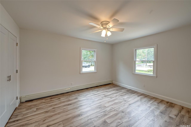 empty room with a baseboard heating unit, a ceiling fan, light wood-style flooring, and a healthy amount of sunlight