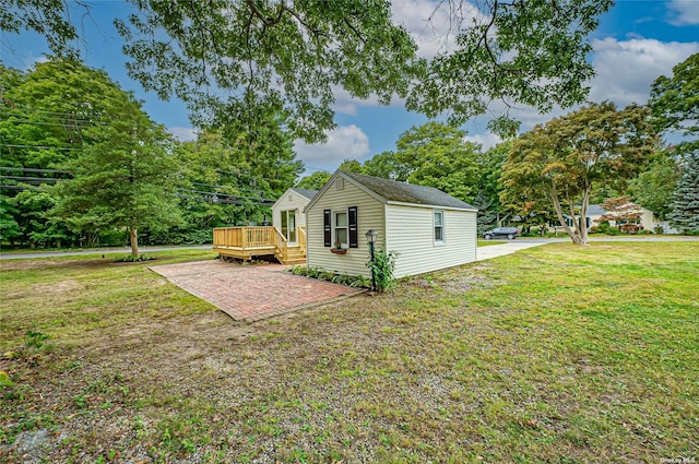 view of side of property featuring a deck, a patio, and a yard