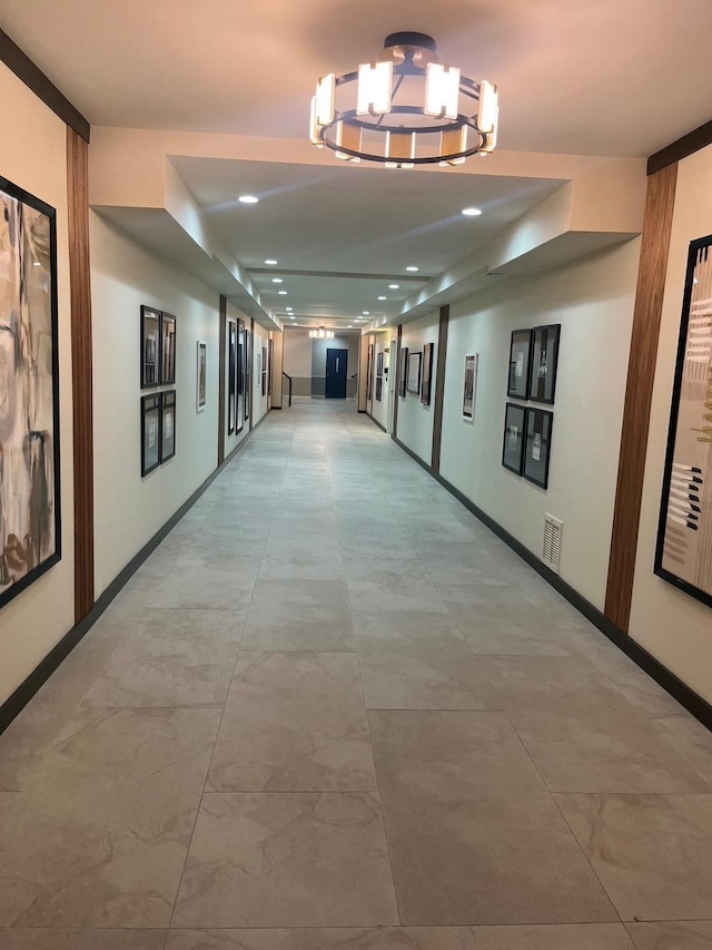 hall with a chandelier, visible vents, and baseboards