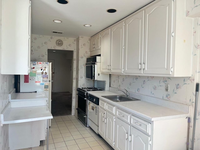 kitchen with wallpapered walls, range with gas stovetop, dishwasher, light countertops, and a sink