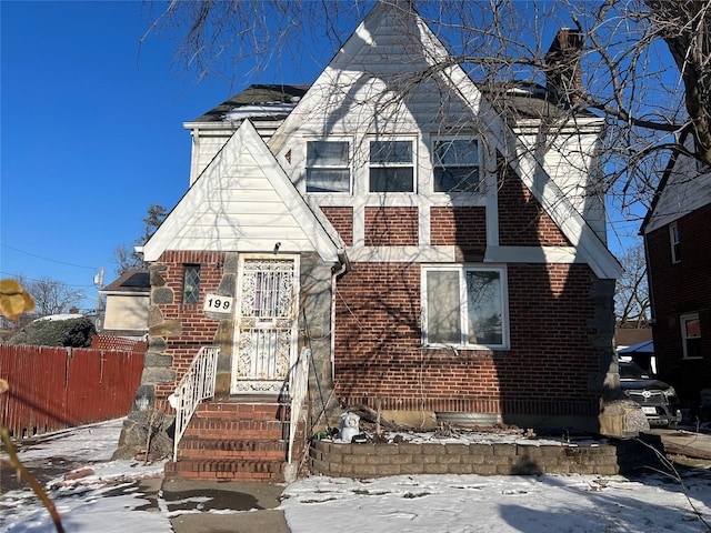 view of front of house with a chimney, fence, and brick siding