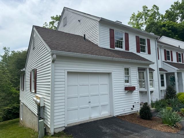 view of property exterior featuring a garage, aphalt driveway, and roof with shingles