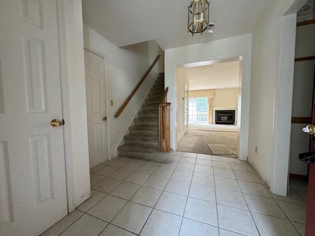 entryway with light tile patterned floors, stairs, and a glass covered fireplace