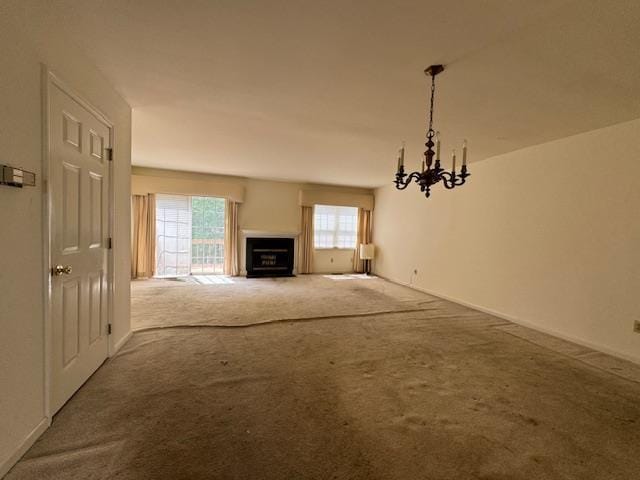 unfurnished living room with carpet, a fireplace, and an inviting chandelier