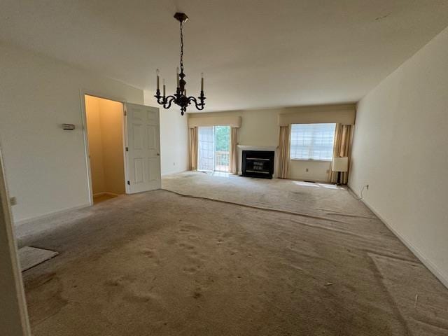 unfurnished living room with a fireplace, carpet flooring, and an inviting chandelier