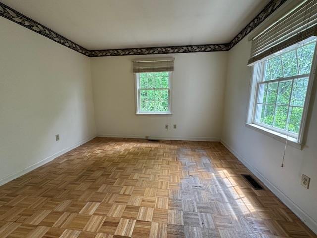 unfurnished room with a wealth of natural light, visible vents, and baseboards