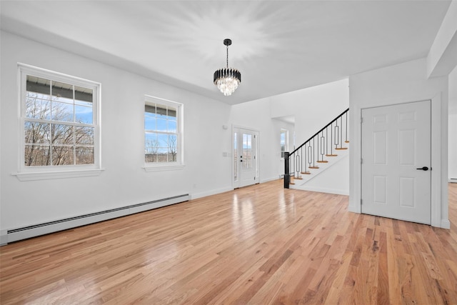 entryway featuring a baseboard radiator, light wood-style flooring, stairway, a chandelier, and baseboards