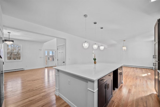 kitchen featuring light wood-style floors, light countertops, a center island, an inviting chandelier, and pendant lighting