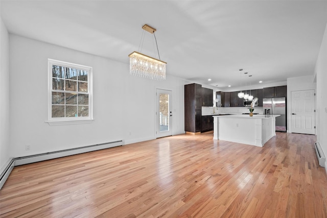 kitchen with a chandelier, light wood-style flooring, a baseboard heating unit, stainless steel appliances, and light countertops