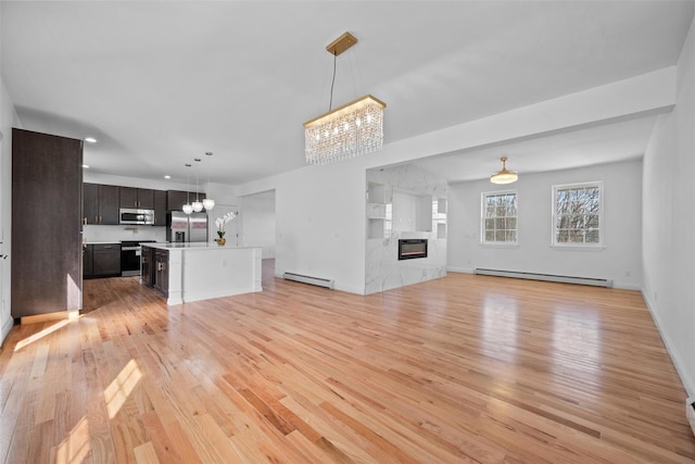 unfurnished living room with a baseboard heating unit, a baseboard radiator, a chandelier, and a high end fireplace