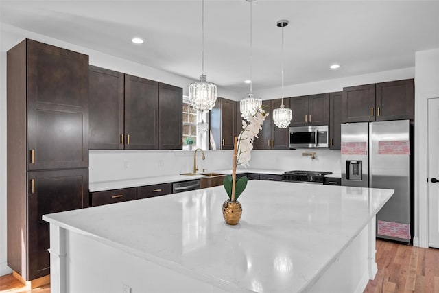 kitchen with dark brown cabinetry, stainless steel appliances, light wood-type flooring, a sink, and recessed lighting